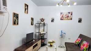 Een woonkamer met een televisie, bank en decoratieve accessoires.