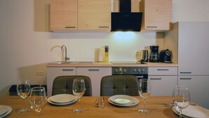 A kitchen with wooden cabinets, a stove, and a dining table set with plates and wine glasses.