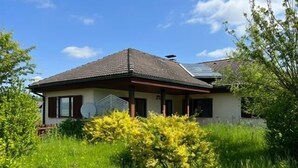 A two-story house with a sloped roof, a satellite dish, and a small porch.