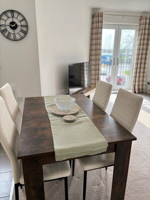 Enjoy meals in this dining area with a table for four, a large window, and a mounted clock.