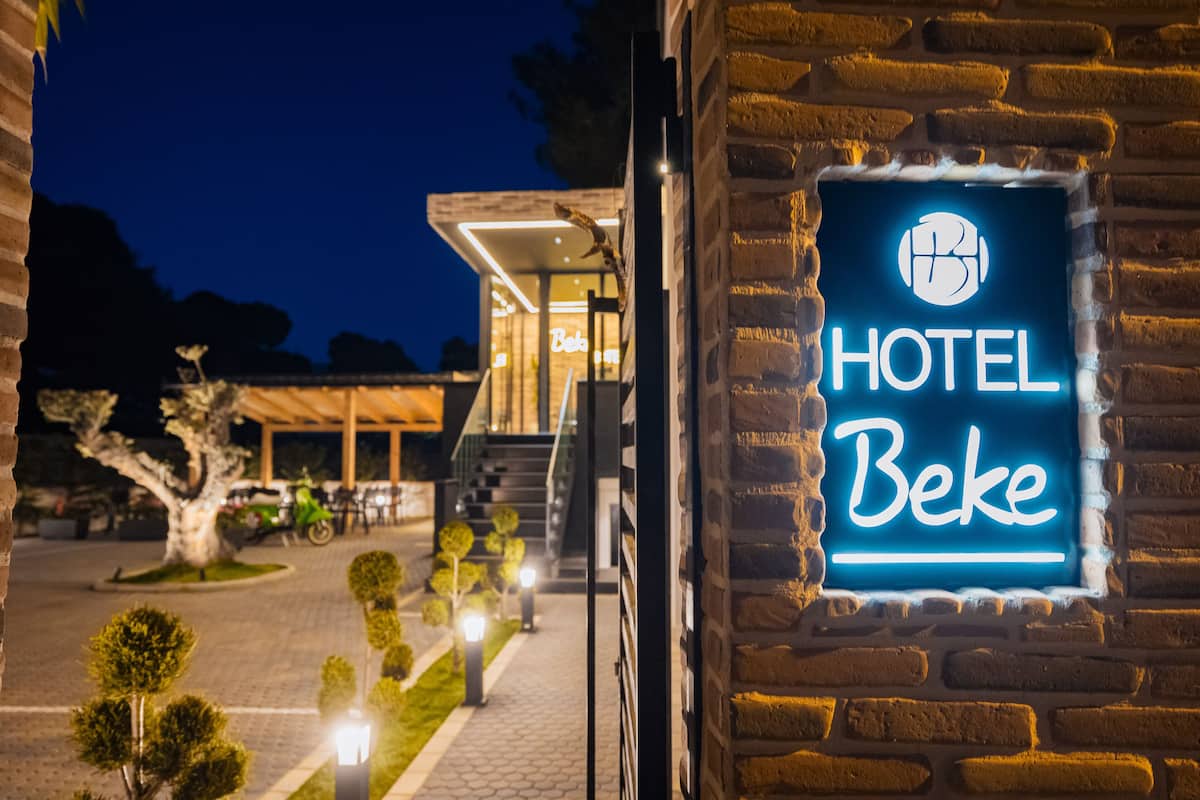 A hotel sign with a neon light and a brick wall.