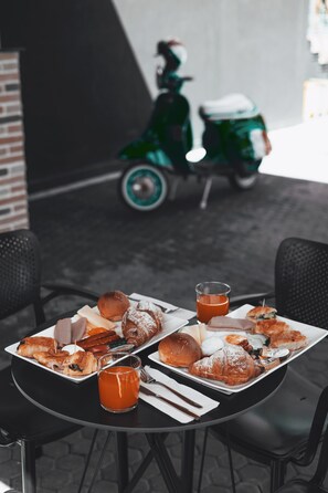 Una mesa con pasteles, un vaso de jugo y una moto en el fondo.