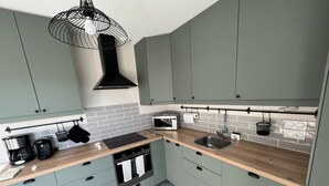 A modern kitchen with grey cabinets, a wooden countertop, a built-in oven, a microwave, and a hanging light fixture.