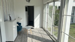 A modern bedroom with a large bed, a bedside table, a window, and a view of the outdoors.