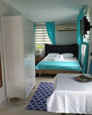 A bedroom with a bed, a nightstand, a wardrobe, and a window with curtains. - Rastgele Otel (Seferihisar)
