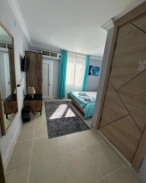 Un dormitorio con cama, cómoda, espejo, televisor y armario.