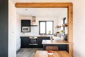 Una cocina moderna con armarios oscuros, un microondas, un horno y un comedor con mesa y sillas.
