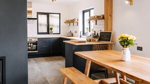 A modern kitchen with dark cabinetry, a wooden island, and a welcome sign. - Modern balcony property, Sea views over Newgale (Newgale)