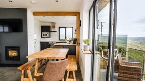 A modern kitchen with a large island, a dining area with wooden furniture, and a balcony with wicker chairs. - Modern balcony property, Sea views over Newgale (Newgale)
