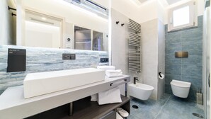 Een moderne badkamer met een grote spiegel, een witte wastafel, een toiletbril en een douchegedeelte.