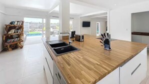 Una cucina moderna con piano di lavoro in legno, lavello incassato e una libreria.