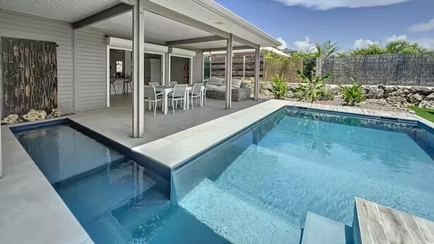 Una casa moderna con piscina, patio coperto e zona relax all'aperto.