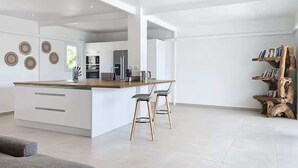 Una cucina moderna con isola centrale, sgabelli da bar e una libreria.