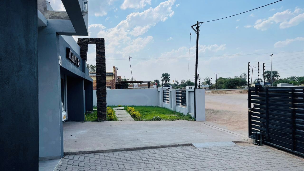 A modern building with a gated entrance, a paved pathway, and a small garden area.