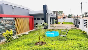Ein modernes Haus mit Swimmingpool, einer roten und grauen Fassade und einem gepflegten Rasen.