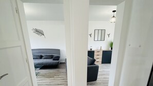 En hall med trägolv som leder till ett vardagsrum med en soffa och ett soffbord.