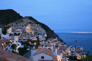 Uma cidade costeira com edifícios de vários andares, alguns com varandas, e vista para o mar.