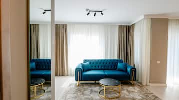 Uma sala de estar moderna com um sofá azul, duas mesas redondas e um lustre.
