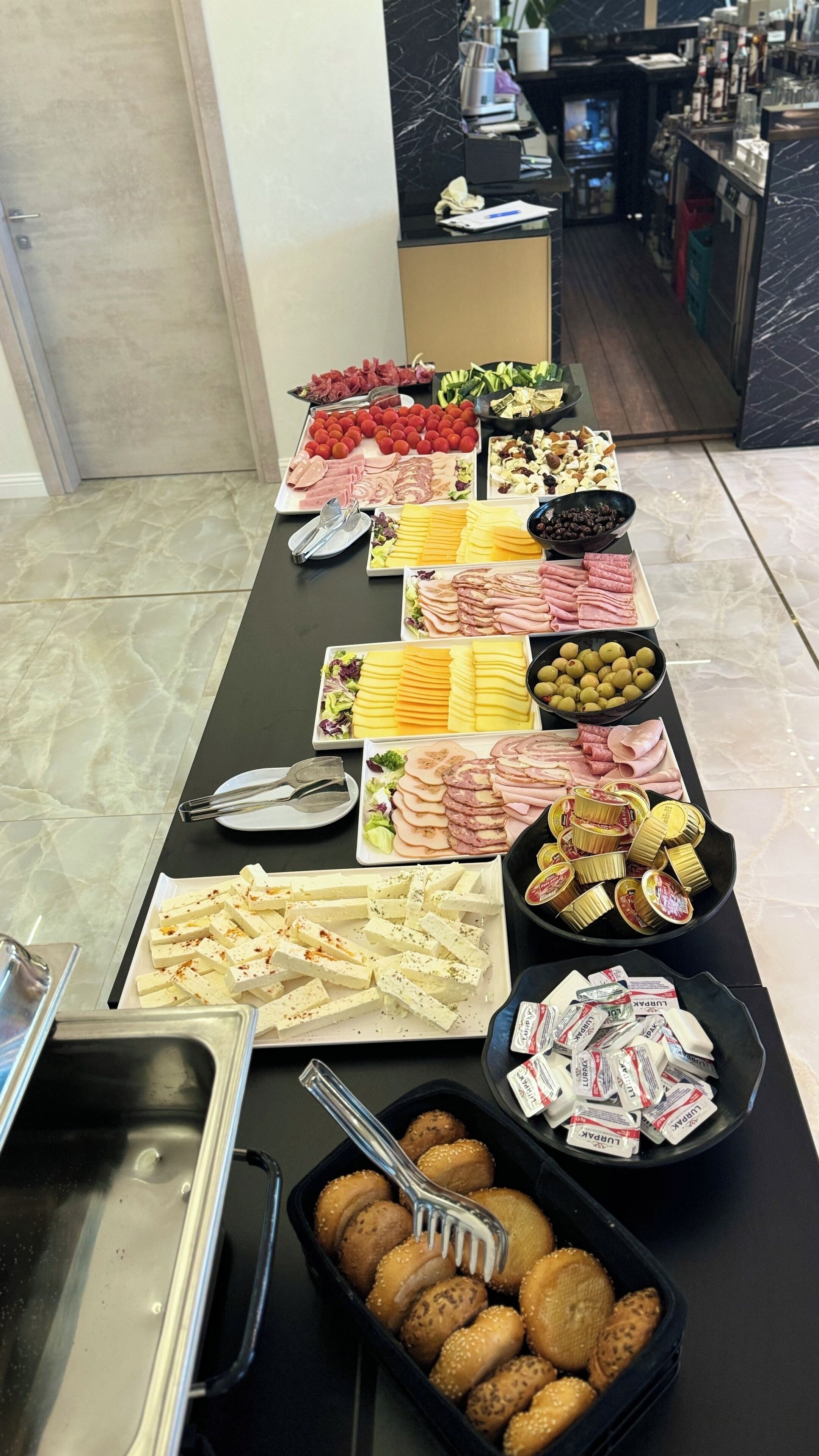 A buffet table with various food items including meats, cheeses, and salads.