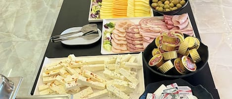 A buffet table with various food items including meats, cheeses, and salads.