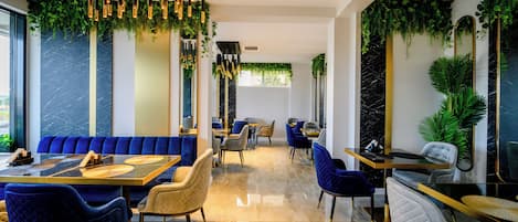 A modern restaurant interior with seating arrangements, hanging lights, and green plants.