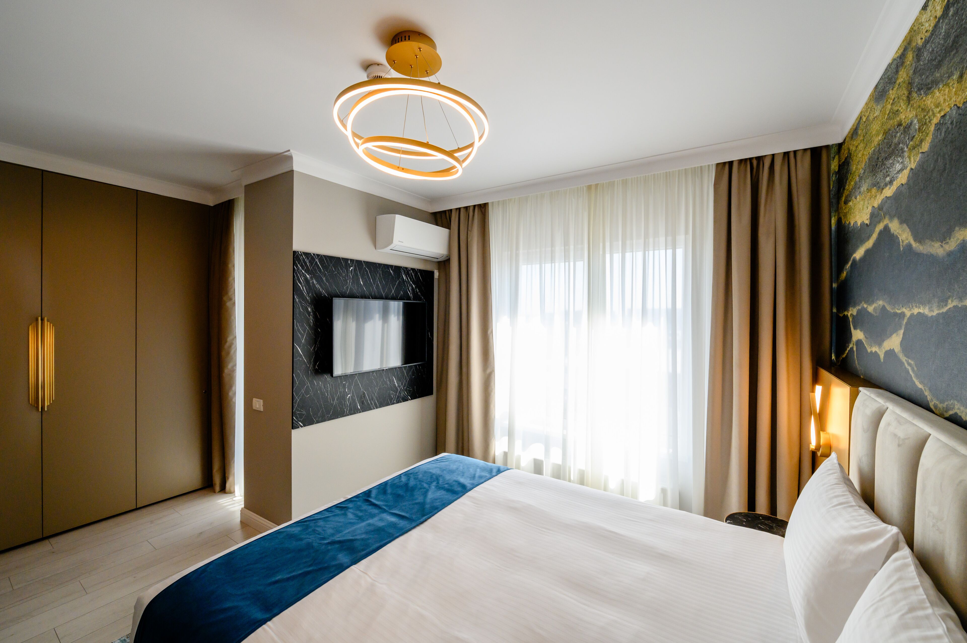 Une chambre d’hôtel moderne dotée d’un grand lit, d’un téléviseur à écran plat fixé au mur et d’un luminaire au plafond.