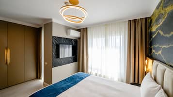 Una habitación de hotel moderna con una cama grande, un televisor de pantalla plana montado en la pared y una lámpara en el techo.