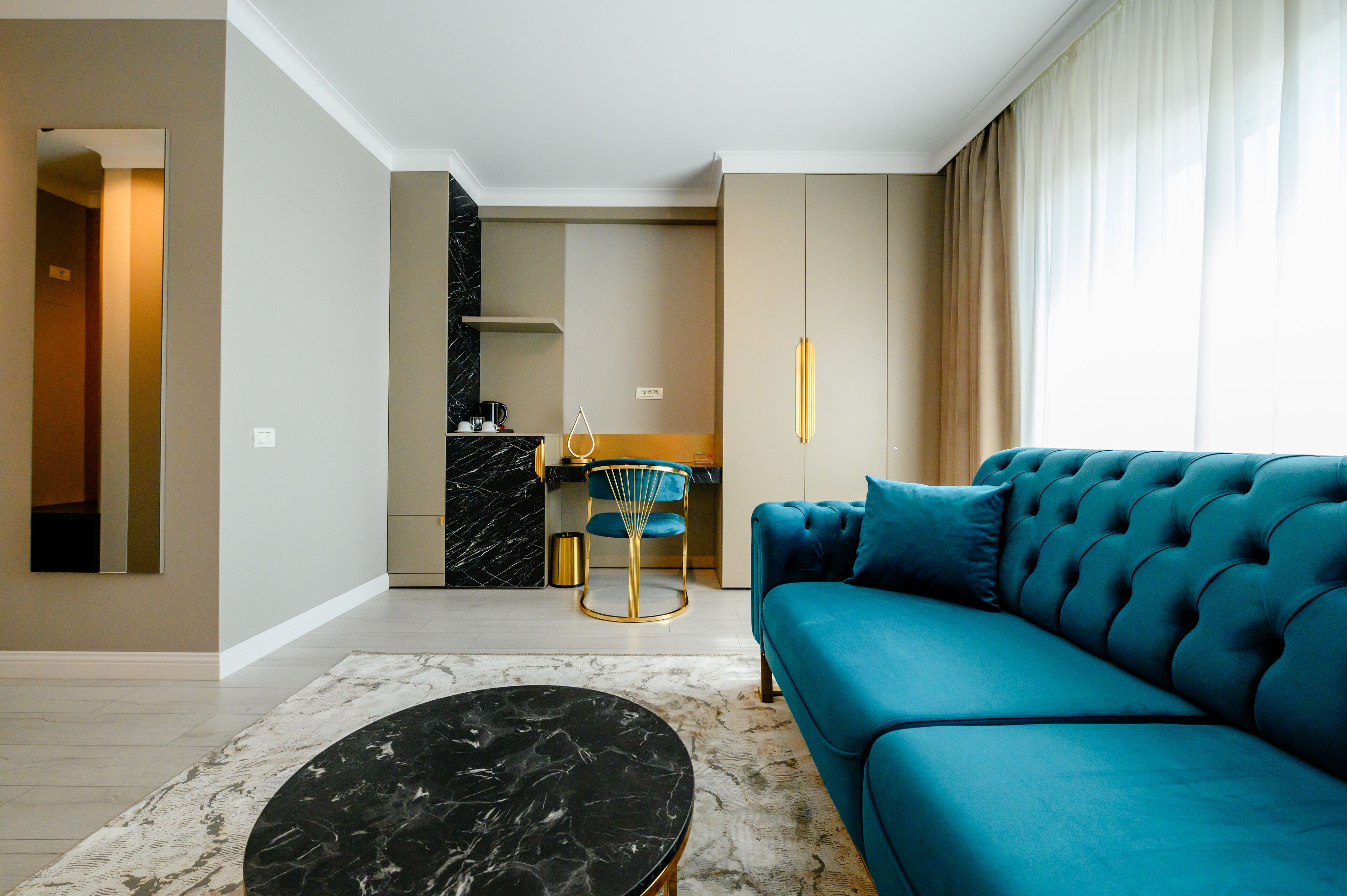 A modern living room with a blue sofa, a black marble coffee table, and a kitchen area in the background.
