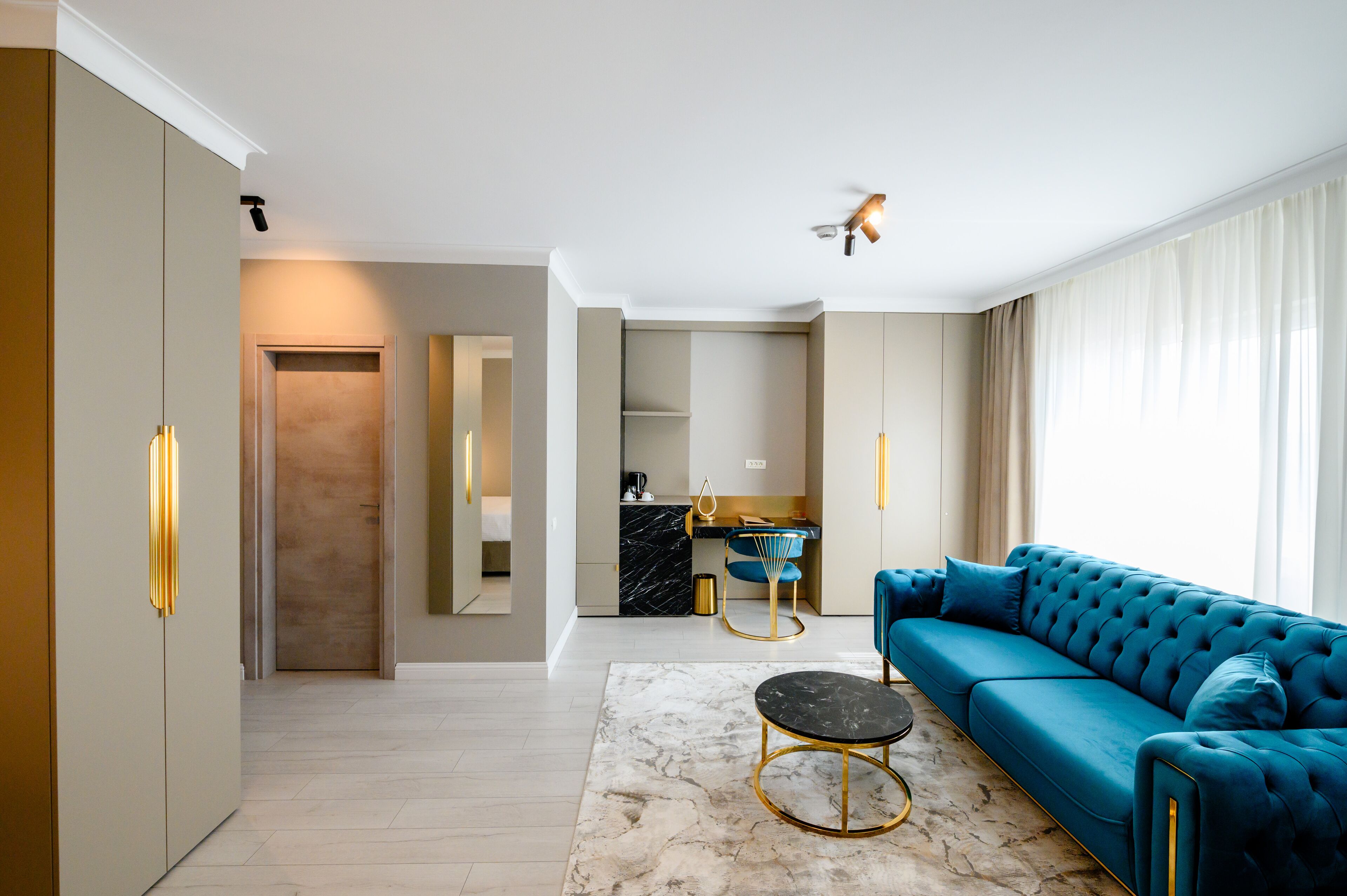 A modern living room with a blue sofa, a marble coffee table, and a kitchen in the background.