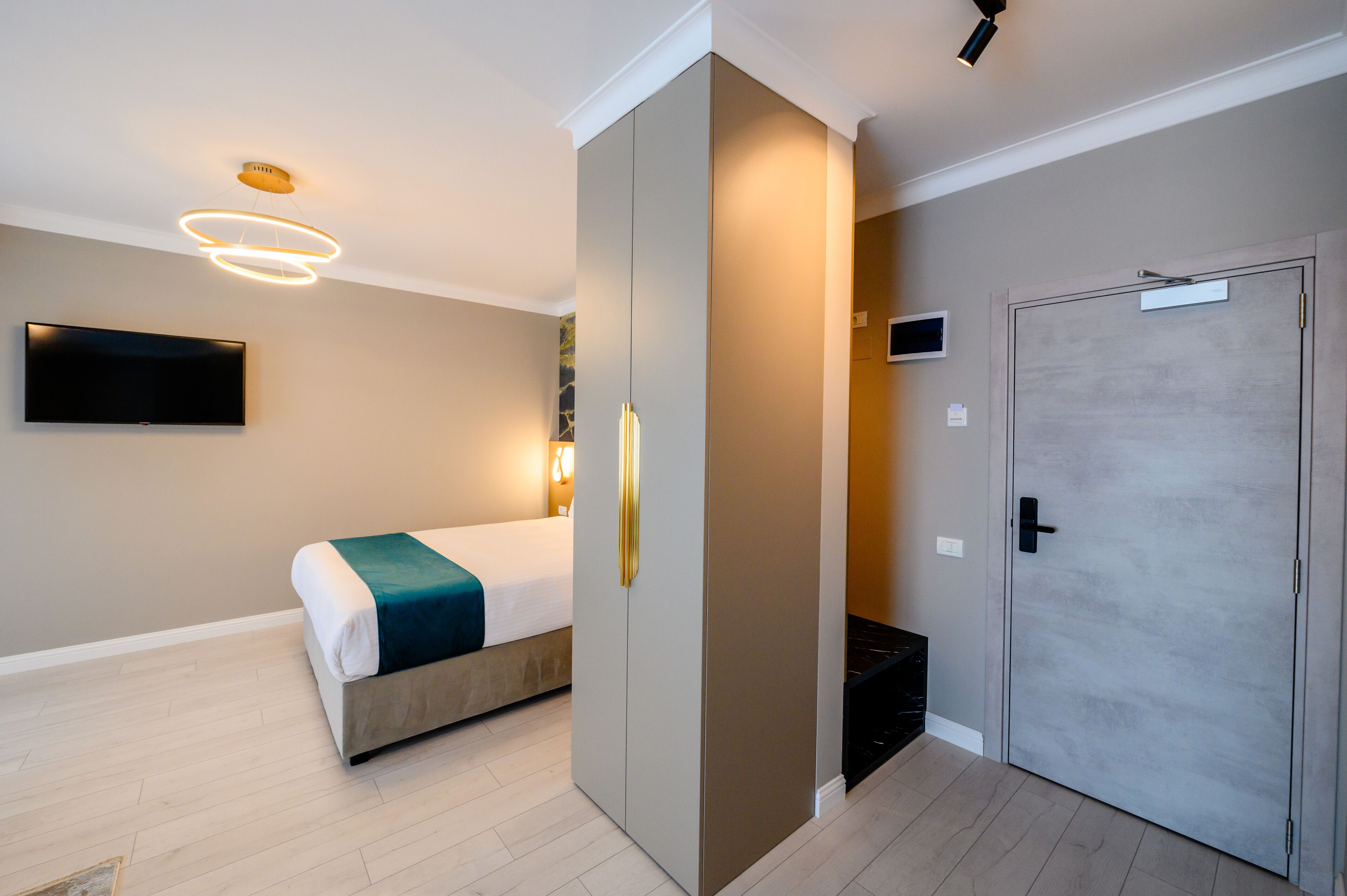 Una habitación de hotel moderna con cama, armario, televisor y puerta.