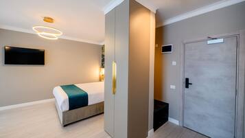 Una habitación de hotel moderna con cama, armario, televisor y puerta.
