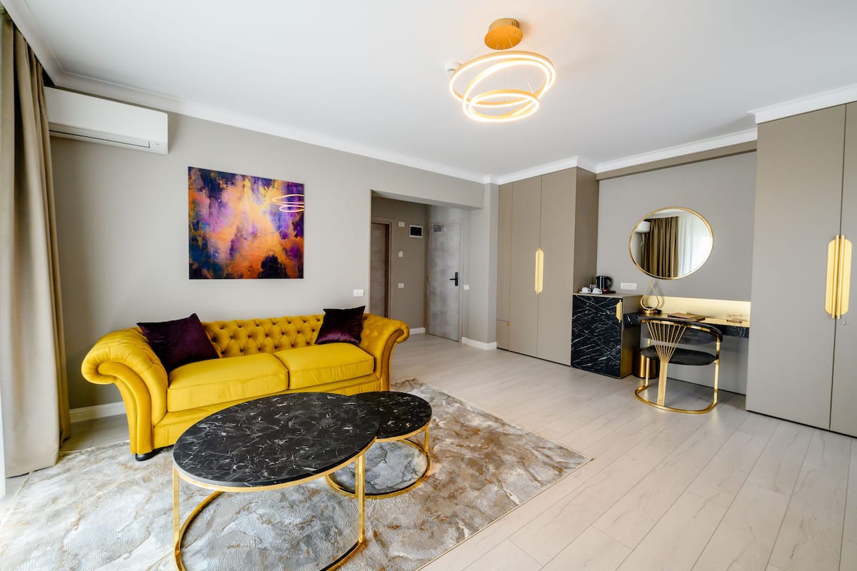 A modern living room with a yellow sofa, a black marble coffee table, and a contemporary light fixture.