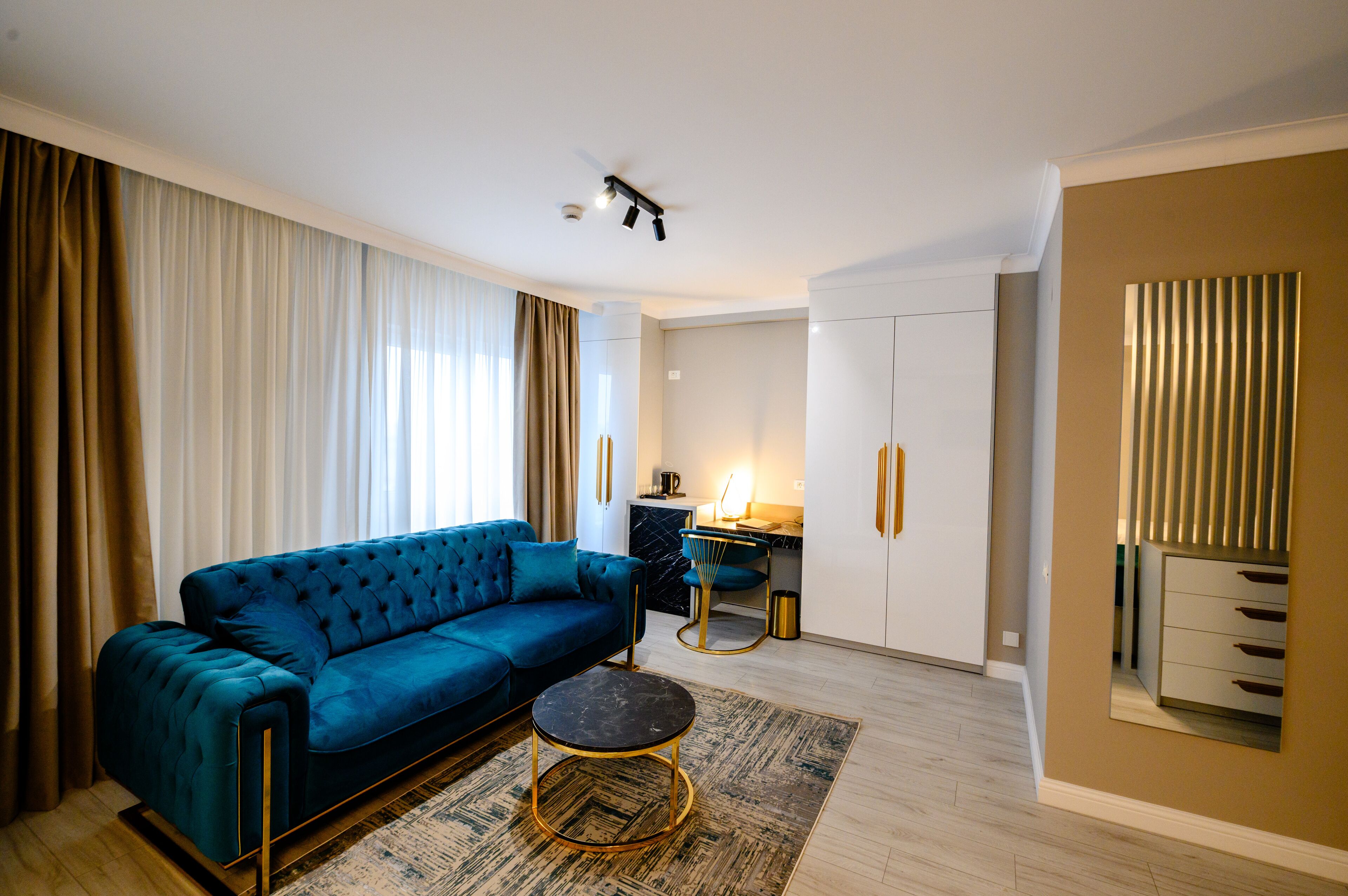En moderne stue med en blå sofa, et rundt sofabord og et køkken i baggrunden.