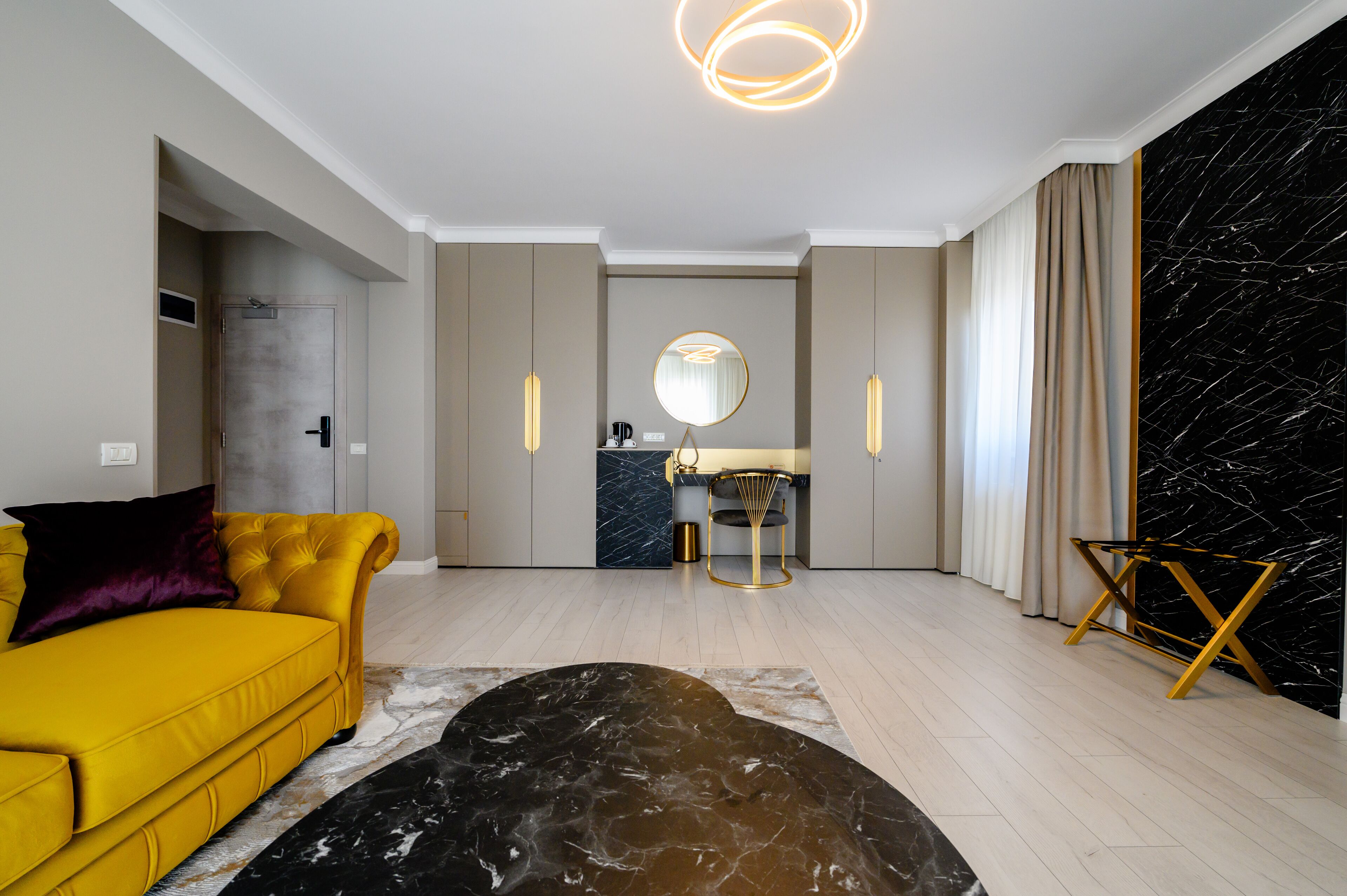 Un salon moderne avec un canapé jaune, une table basse en marbre et un coin cuisine doté d’un pare-feu en marbre.