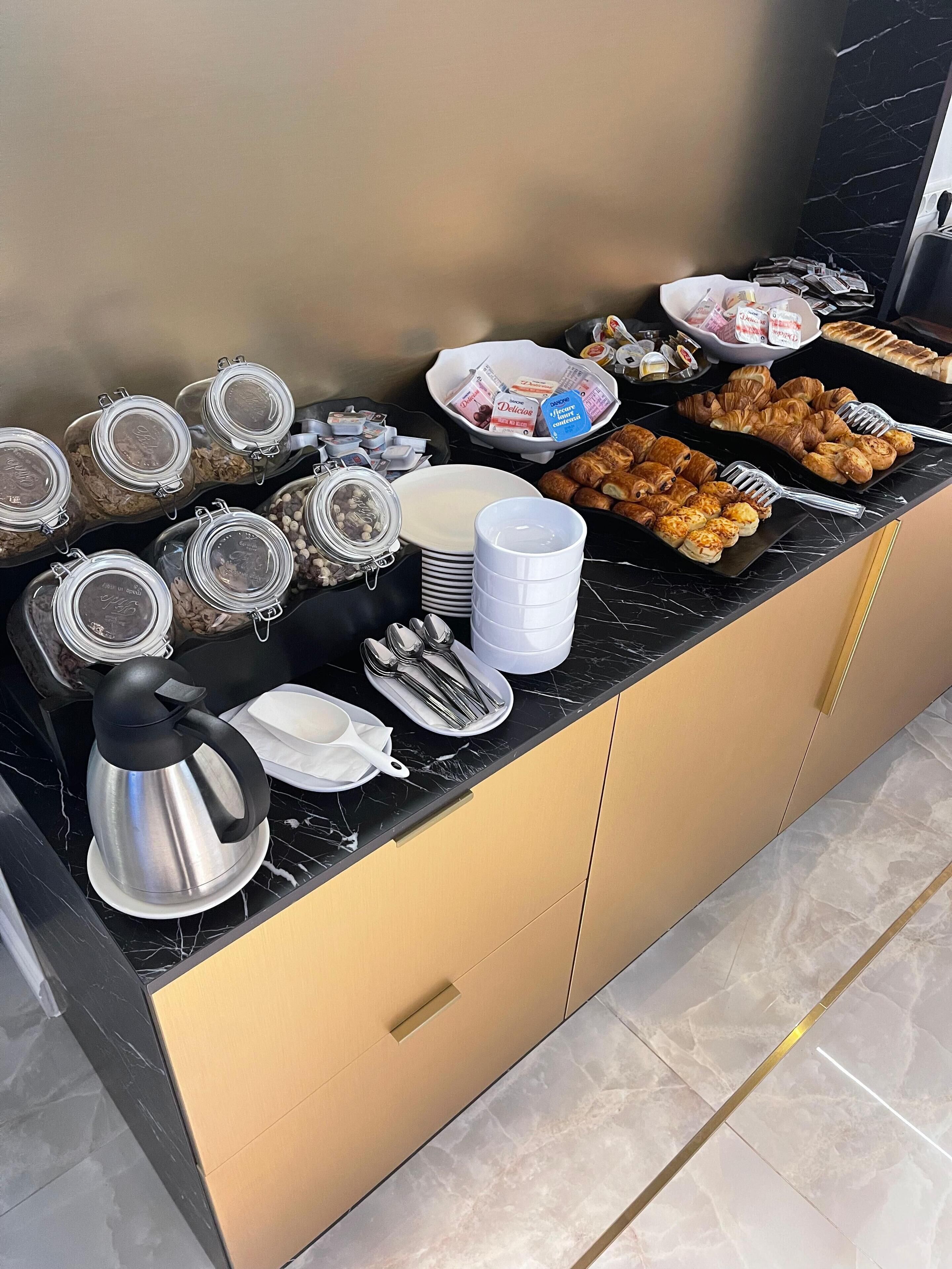 Un bufé con diversos alimentos y utensilios sobre una encimera de mármol.