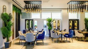 Un moderno vestíbulo de hotel con zona de estar, espejos grandes y lámparas colgantes.