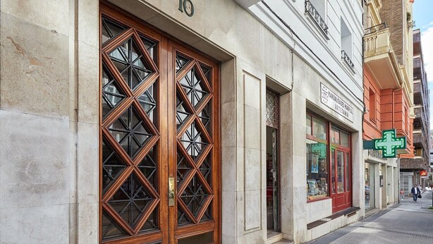 A building with large wooden doors and a sign for a pharmacy.