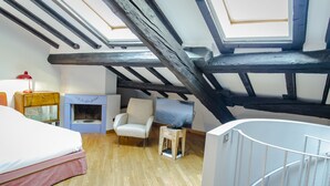 A room with a bed, a chair, a small table, a fireplace, and a skylight. - San Fermo Apartment (Milan)