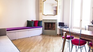 A room with a built-in bench, a fireplace, a dining table with chairs, and a large mirror on the wall. - San Fermo Apartment (Milan)