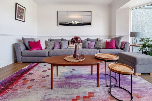 A modern living room with a grey sofa, a wooden coffee table, and a colorful rug. - Fresh & Stylish | Ocean View | Donegal Town & Bay (Tullycullion)