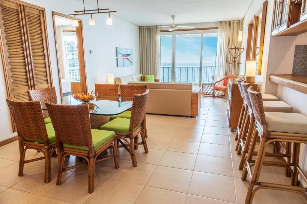 A spacious room with a dining area, a sofa, and a balcony with a view.