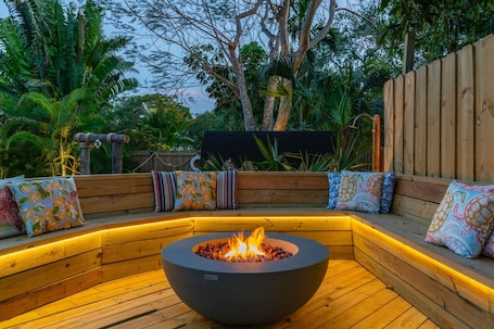 A wooden outdoor seating area with a built-in fire pit.