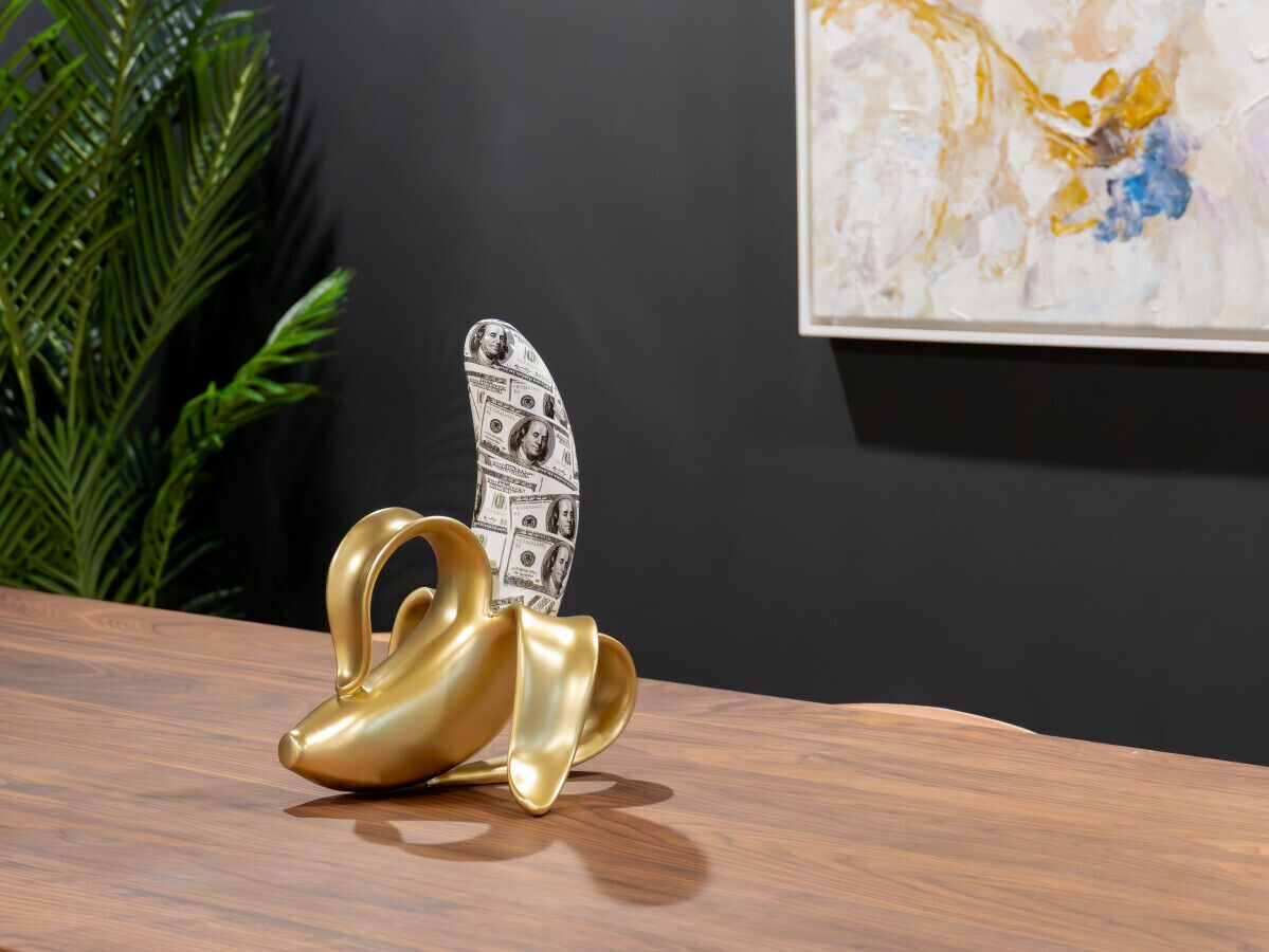 A golden swan-shaped object with a dollar bill pattern on its back, placed on a wooden surface.
