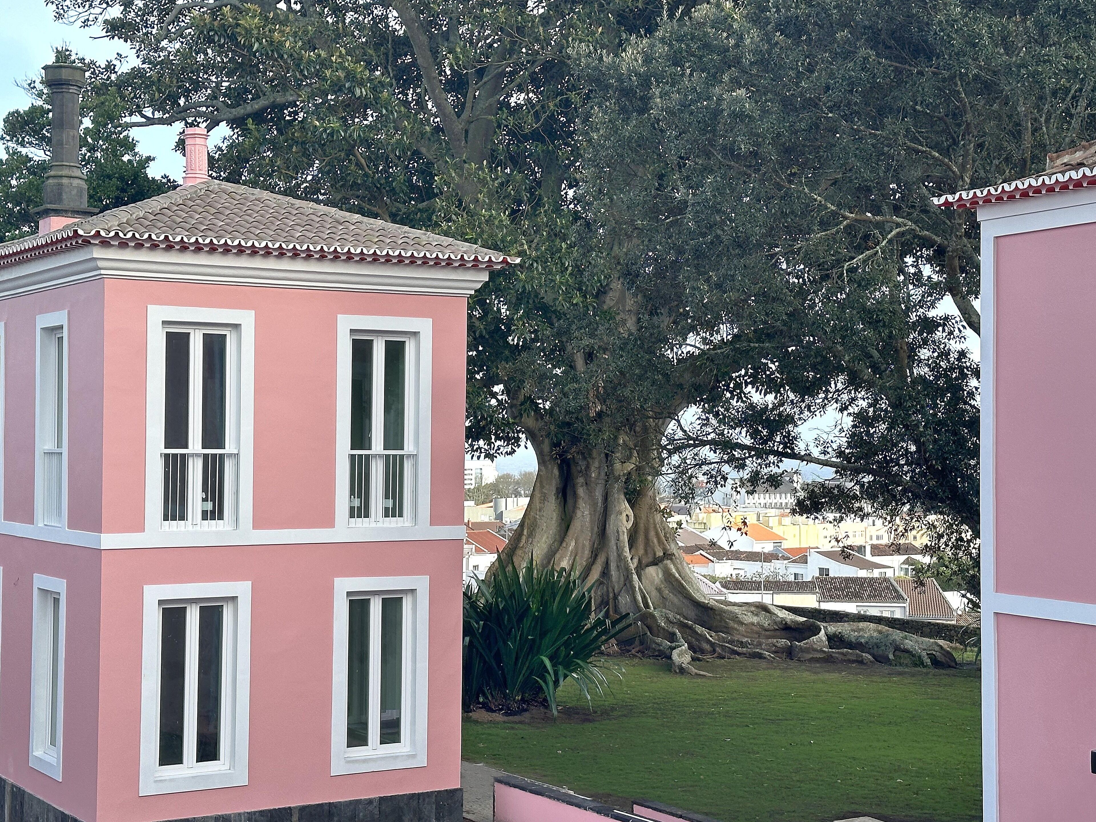 A pink building with white-framed windows and a tiled roof.