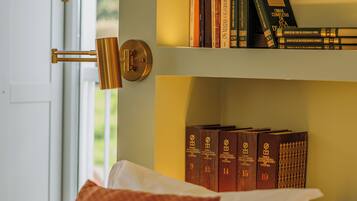 A neatly arranged bedroom with a bed, pillows, and a shelf with books.