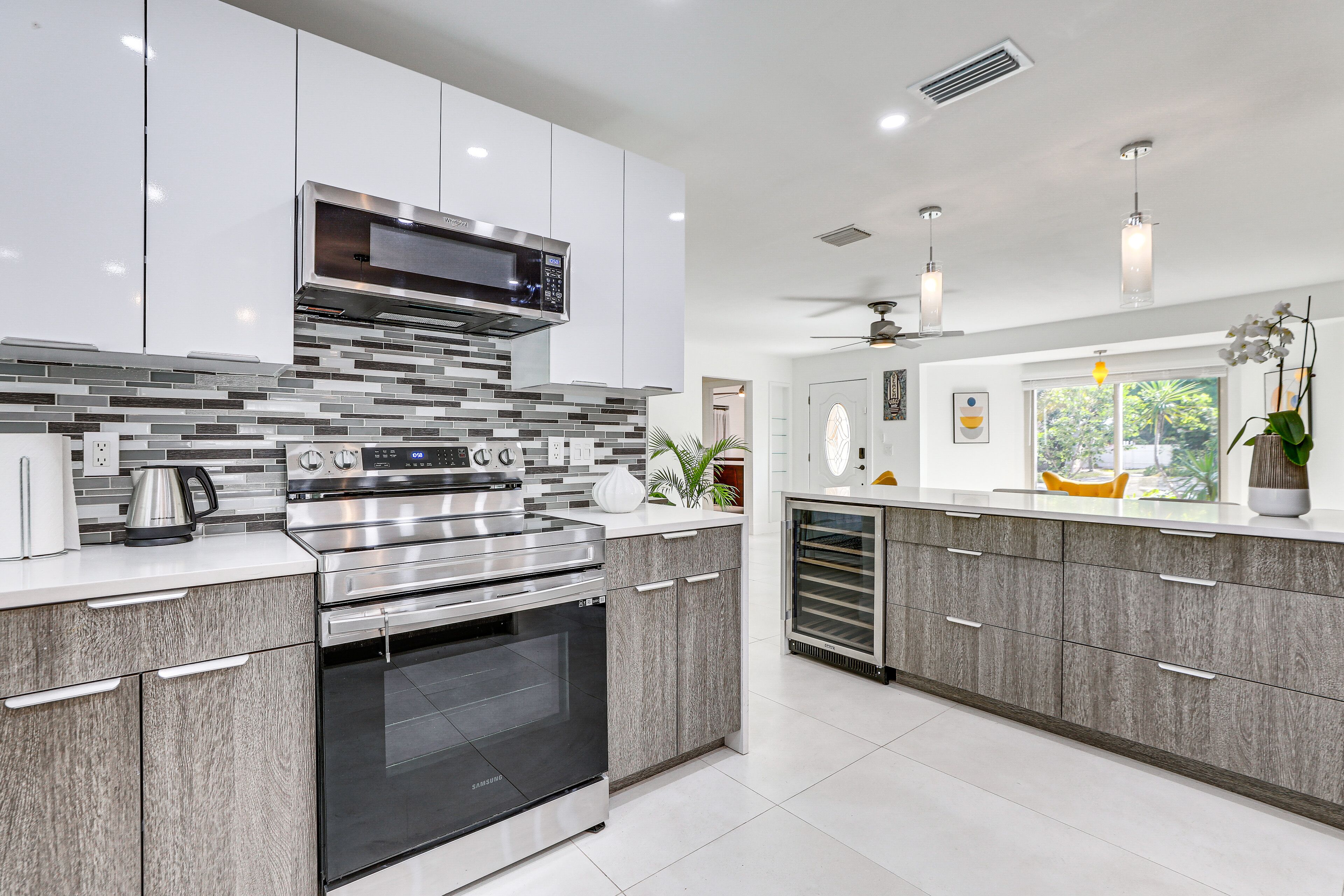 A modern kitchen with stainless steel appliances, grey cabinetry, and a tiled backsplash.