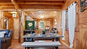 L’intérieur d’un chalet en bois comprend un coin repas, un canapé et une cuisine.