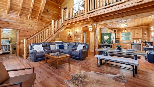 Un intérieur spacieux de chalet en bois, comprenant un salon, un coin repas et une cuisine.
