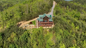 A lodge with a green roof, surrounded by dense forest and a dirt road leading to it. - The Joy Of The Mountain Tops (SEVIERVILLE)