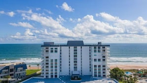 Een meerhoog hotel met een centrale binnenplaats, gelegen nabij een strand met uitzicht op de oceaan.
